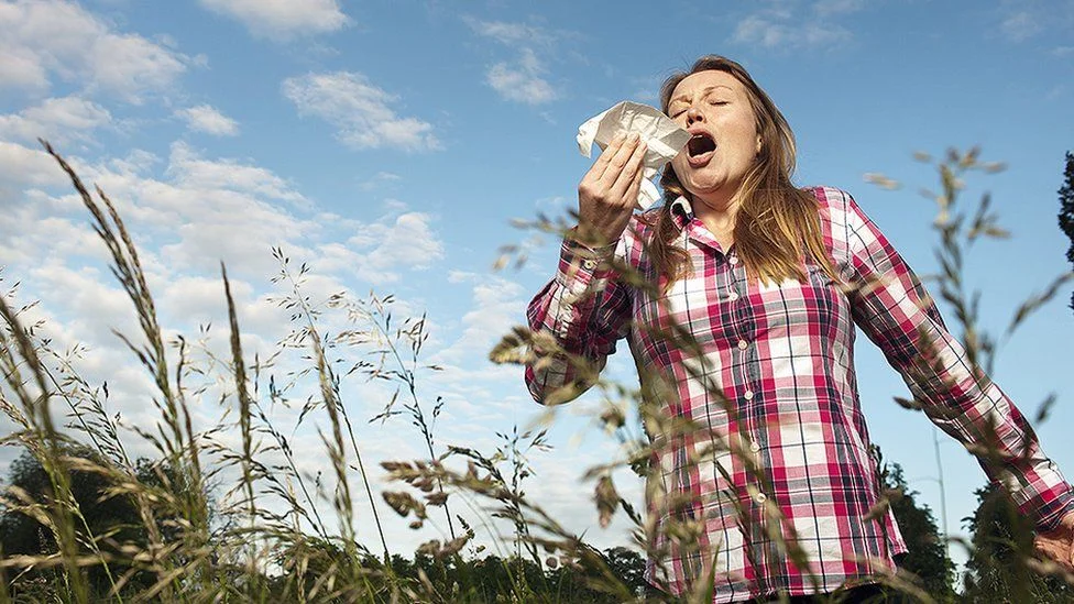 A woman with allergic conditions is yelling in a field.