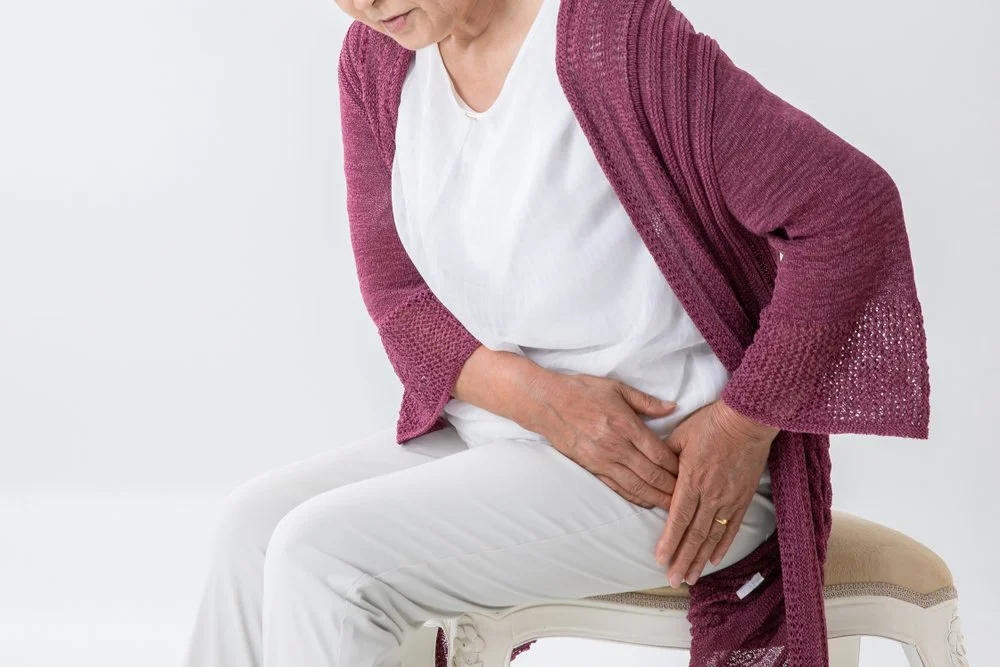 A woman sitting on a chair with her stomach hurting.