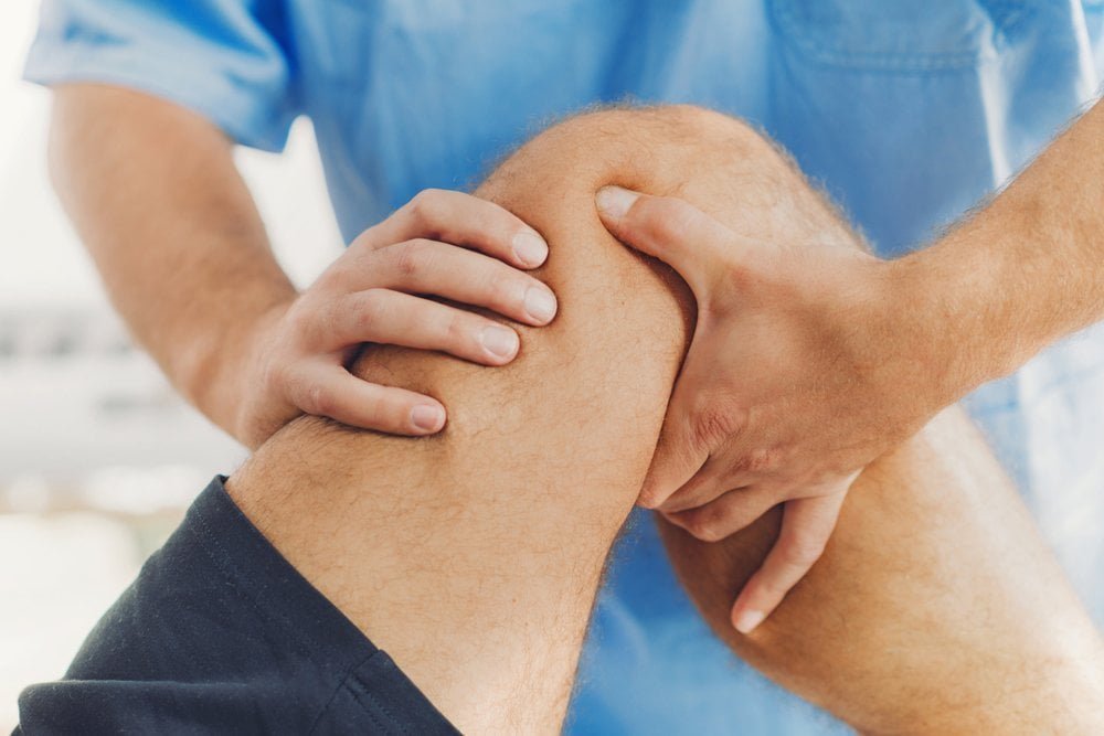 A man is having his knee examined at a sports injury clinic.