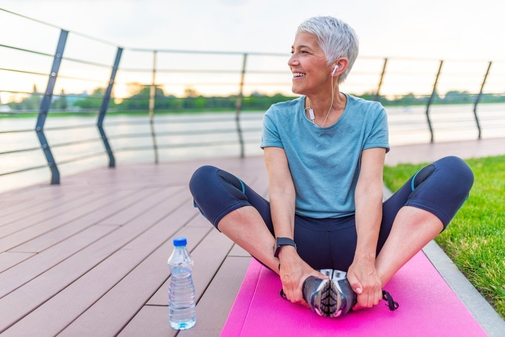 An older woman is sitting on a yoga mat in London.