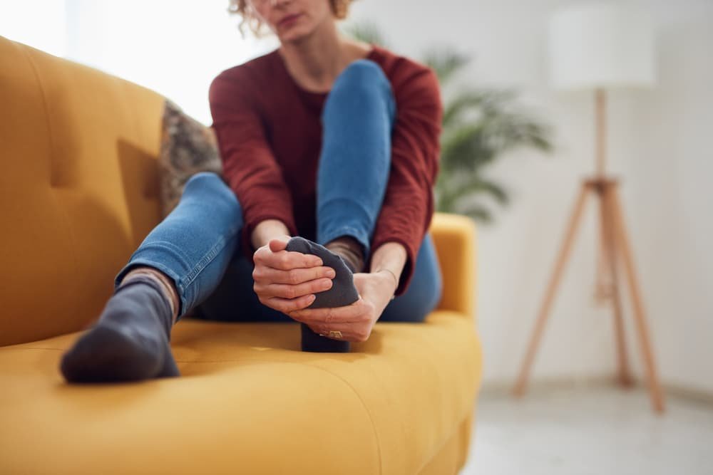 A woman sitting on a yellow couch with her feet up in London.