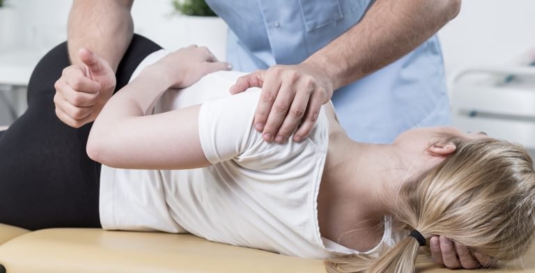 A woman undergoing a back examination in London by a physiotherapist.