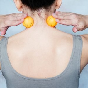 A woman using a tennis ball for self-help relief from headaches.